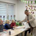 Na zdjęciu widoczny wójt, który rozdaje odblaskowe kamizelki seniorom.