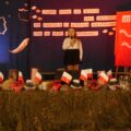 Na zdjęciu widoczna dziewczynka podczas występu na scenie. Scena udekorowana jest w narodowe barwy.