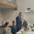 Na fotografii widoczny wójt, który przemawia podczas spotkania. Na zdjęciu widoczne także inne osoby.