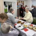 Na fotografii widoczni seniorzy podczas dzielenia się opłatkiem.
