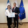 Na fotografii wójt wraz z sołtysem Błotnicy pozują z czekiem. W tle widoczne są flagi: Polski, Unii Europejskiej oraz z herbem gminy Przemęt.