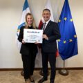 Na fotografii wójt wraz z sołtysem Bucza pozują z czekiem. W tle widoczne są flagi: Polski, Unii Europejskiej oraz z herbem gminy Przemęt.