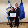 Na fotografii wójt wraz z sołtysem Kluczewa pozują z czekiem. W tle widoczne są flagi: Polski, Unii Europejskiej oraz z herbem gminy Przemęt.
