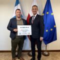 Na fotografii wójt wraz z sołtysem Siekowa pozują z czekiem. W tle widoczne są flagi: Polski, Unii Europejskiej oraz z herbem gminy Przemęt.