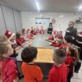 Na zdjęciu widoczne dzieci, które z zaciekawieniem słuchają pań z KGW.