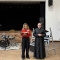 Na zdjęciu widoczna nauczycielka oraz ksiądz, którzy przemawiają podczas wigilii.