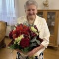 Na fotografii uśmiechnięta jubilatka pozuje z bukietem kwiatów.