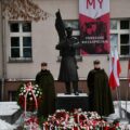 Na zdjęciu widoczni są dwaj mężczyźni, którzy stoją na warcie przy pomniku.