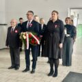 Na fotografii widoczna delegacja złożona z wójta Janusza Frąckowiaka, kierownik wydziału oświaty Marty Sobierajskiej oraz pana Antoniego Fornalskiego. Delegacja składa wiązankę pod Ścianą Patrona.