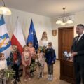 Na zdjęciu widoczny wójt oraz dzieci, które stoją z przystrojonymi gałązkami i koszyczkami.